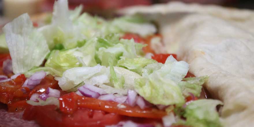 Photo of lettuce, tomotoes, and onions being laid on a Panini at GJP Italian Eatery in Oswego, NY.
